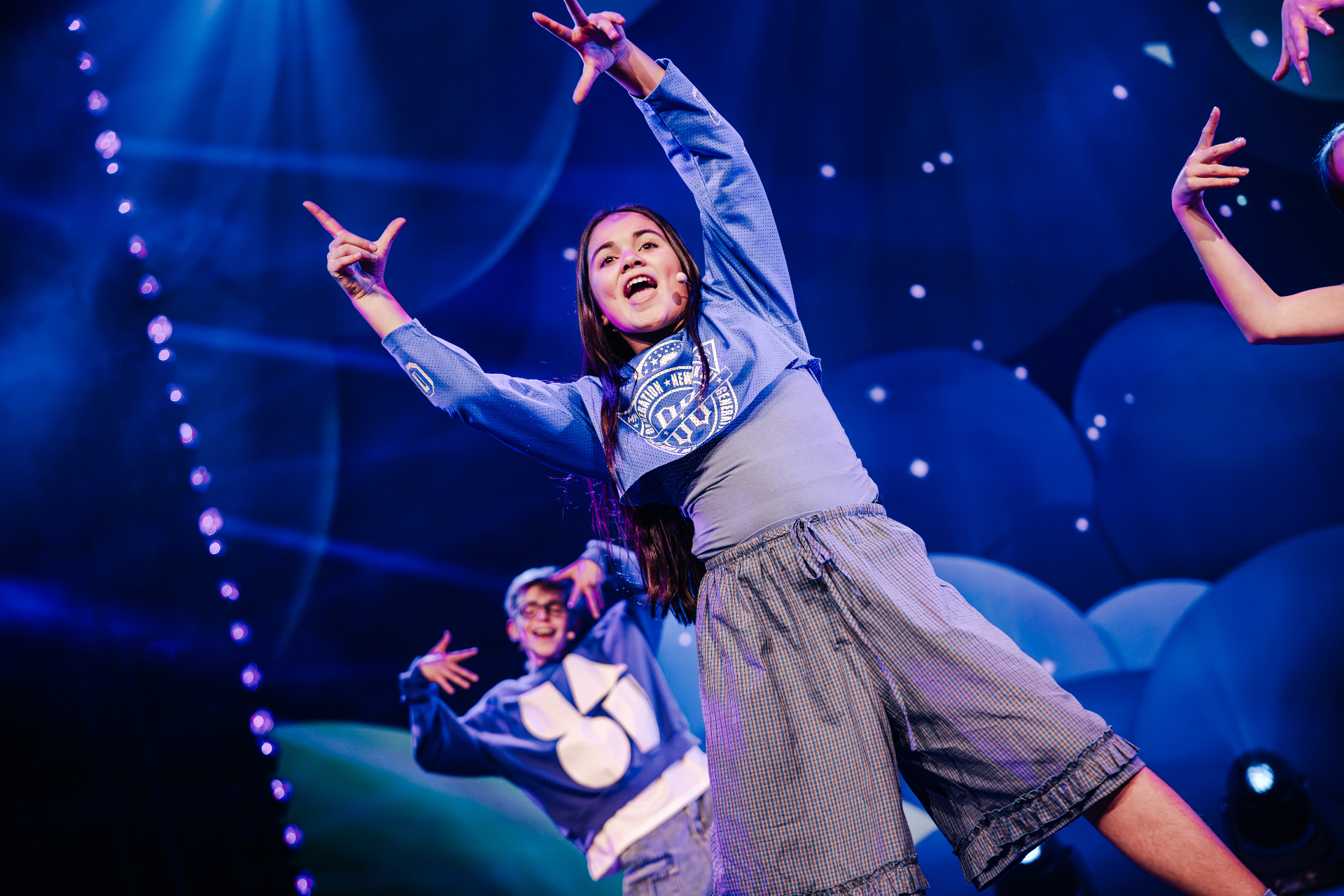 Marisa met armen omhoog tijdens de show in blauw licht
