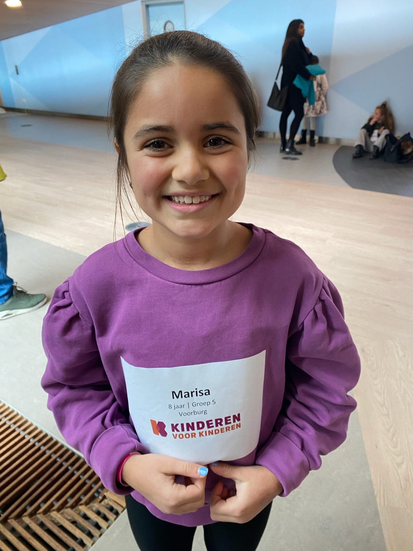 Marisa lacht met haar Kinderen voor Kinderen naamkaart op haar trui