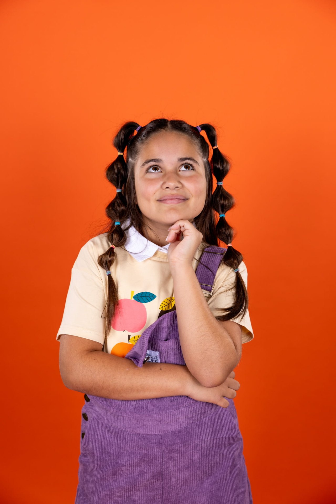 Portret van Marisa met vrolijke vlechtjes voor oranje achtergrond